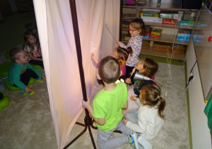 Dzieci animują sylwetami tworząc teatrzyk cieni